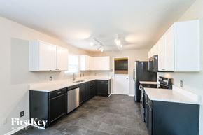 Noblesville house for rent - a black and white kitchen with white cabinets and black appliances