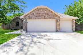 Norman house for rent - a white garage door on a brick house with a white driveway
