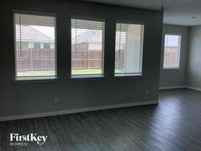 Forney house for rent - an empty living room with three windows and a wood floor