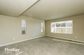 Colorado Springs house for rent - A spacious empty room with a carpeted floor and two windows.