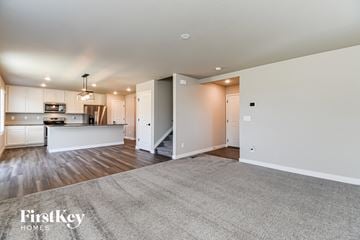 Colorado Springs house for rent - A spacious living room with a kitchen in the background and a carpet on the floor.