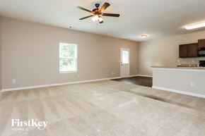 Hampton house for rent - an empty living room with a ceiling fan and a kitchen