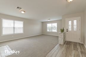 Vail house for rent - A well-lit, empty room with a door, windows, and a carpeted floor.