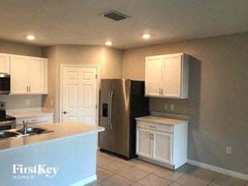 Fort Myers house for rent - a kitchen with white cabinets and a stainless steel refrigerator