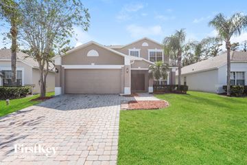 Kissimmee house for rent - a beige house with a driveway and palm trees