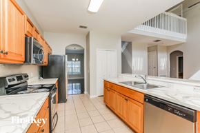 Kissimmee house for rent - a kitchen with marble counter tops and wooden cabinets and a sink