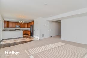 Colorado Springs house for rent - an empty living room and kitchen with white walls and wood cabinets