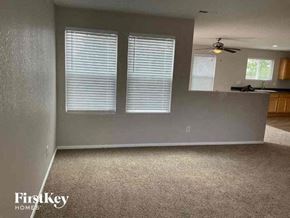 Lochbuie house for rent - an empty living room with three windows and a ceiling fan