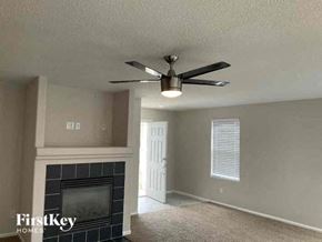 Lochbuie house for rent - a living room with a ceiling fan and a fireplace