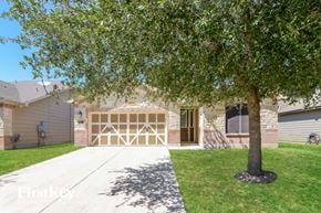 San Antonio house for rent - A tree stands in front of a house with a garage door.