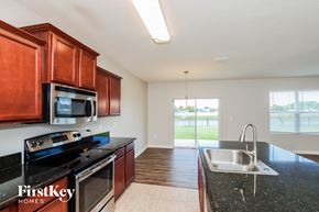 Melbourne house for rent - a kitchen with black granite counter tops and wooden cabinets