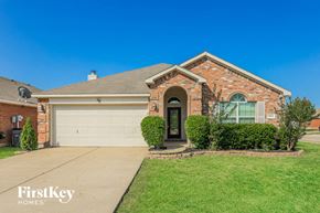 Forney house for rent - A brick house with a garage door and a black door.