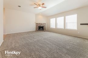 Forney house for rent - A spacious room with a fireplace and a ceiling fan.