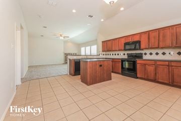 Forney house for rent - A kitchen with wooden cabinets and a black stove top oven.