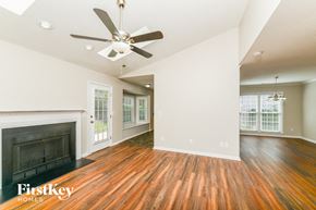 Greensboro house for rent - an empty living room with a fireplace and a ceiling fan