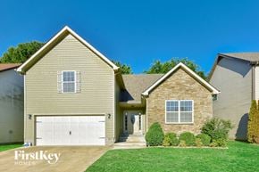 Clarksville house for rent - a tan house with a white garage door and a green lawn