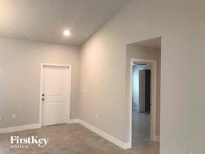 Fort Myers house for rent - an empty living room with a white door and a hallway