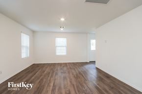 Conroe house for rent - A spacious room with wooden floors and two windows.