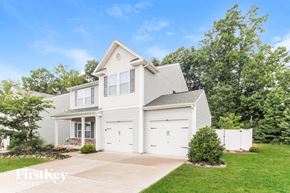 Gastonia house for rent - a white house with two garage doors and a lawn