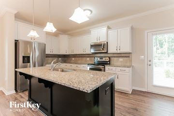 Gastonia house for rent - a kitchen with white cabinets and a granite counter top