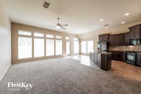 Fresno house for rent - A spacious kitchen and living room with a carpeted floor and a ceiling fan.