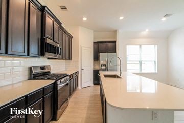 Rosharon house for rent - A kitchen with black cabinets and a stove top oven.