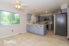 Sharonville house for rent - a large kitchen with blue cabinets and a large window