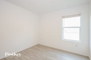 San Antonio house for rent - a bedroom with white walls and a window and wood floors