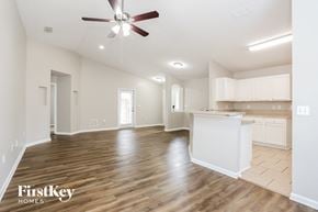 Jacksonville house for rent - an empty living room and kitchen with a ceiling fan