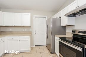 Jacksonville house for rent - a kitchen with white cabinets and stainless steel appliances