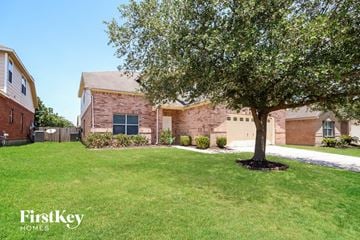 Tomball house for rent - a tree in a yard in front of a brick house