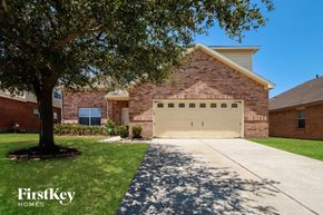 Tomball house for rent - a garage door in front of a brick house with a tree