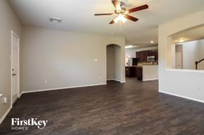 Tomball house for rent - an empty living room with a ceiling fan and a kitchen