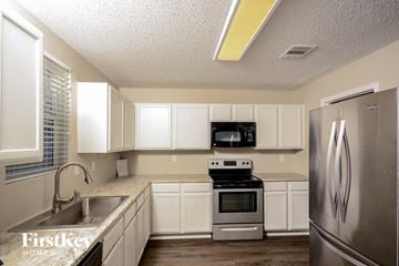 Anna house for rent - A kitchen with white cabinets and a stainless steel refrigerator.