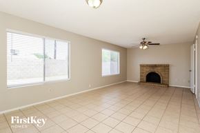 Tempe house for rent - an empty living room with a fireplace and a ceiling fan
