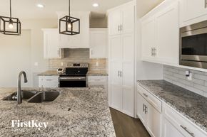 Platte City house for rent - a kitchen with marble counter tops and white cabinets