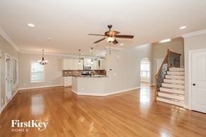 Winston Salem house for rent - A spacious living room with a wooden floor and a staircase leading to the upper floor.