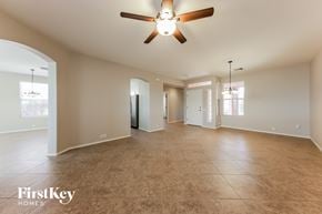 Tucson house for rent - A spacious room with a ceiling fan and light fixture, and a large window with blinds.