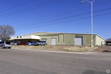 Colorado Springs apartment for rent - A large industrial building with a parking lot in front.