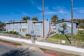 Banning apartment for rent - A building with a blue facade and palm trees in front.