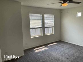 Commerce City house for rent - an empty living room with a ceiling fan and two windows