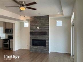Commerce City house for rent - a living room with a fireplace and a ceiling fan