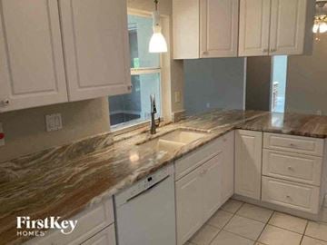 Port Charlotte house for rent - a kitchen with white cabinets and a marble counter top