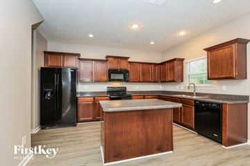 Antioch house for rent - a kitchen with wooden cabinets and a black refrigerator