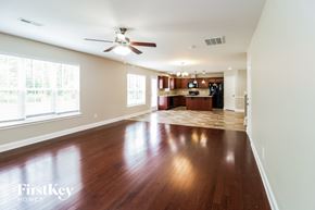 Thomasville house for rent - A spacious living room with wood flooring and a ceiling fan.