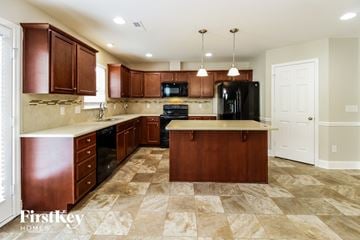 Thomasville house for rent - A kitchen with brown cabinets and a black fridge.