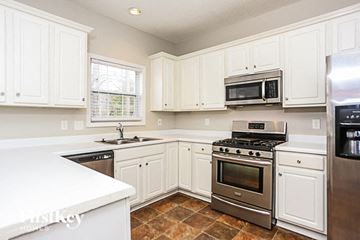 Powder Springs house for rent - A kitchen with white cabinets and a stainless steel refrigerator.