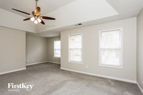 Powder Springs house for rent - A spacious room with a ceiling fan and two windows.