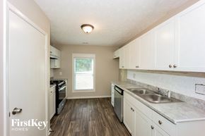 Rex house for rent - a kitchen with white cabinets and a sink and a window