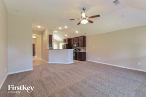 League City house for rent - an empty living room with a ceiling fan and a kitchen